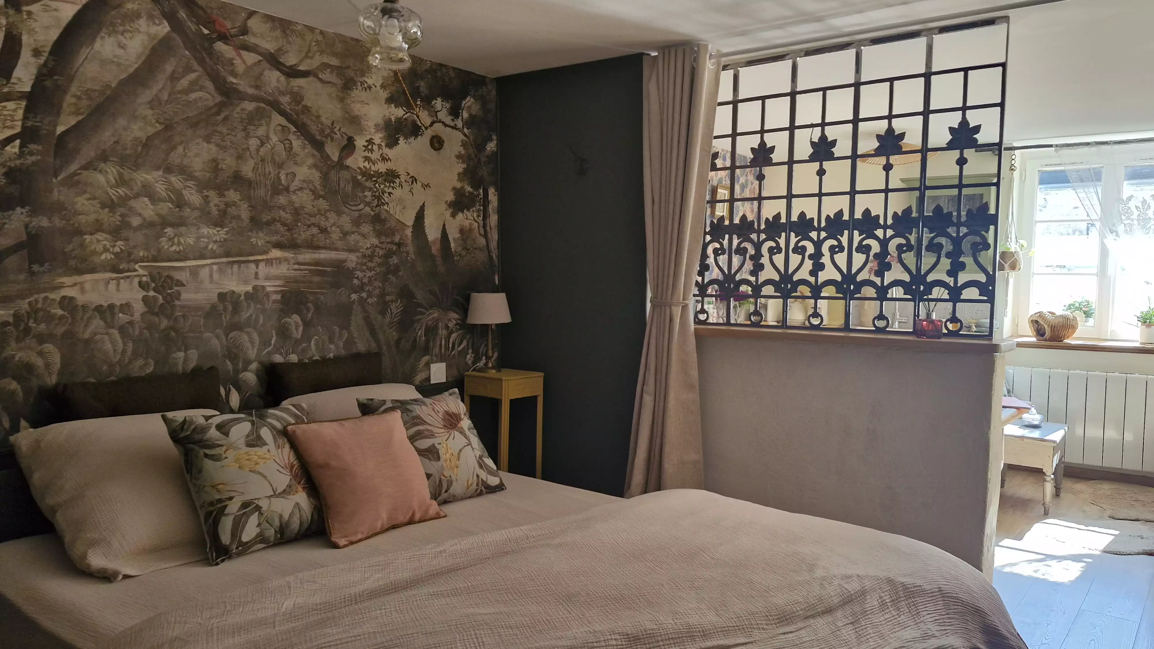 Photo en plan large de la chambre et du lit laissant apercevoir le salon en arrière plan