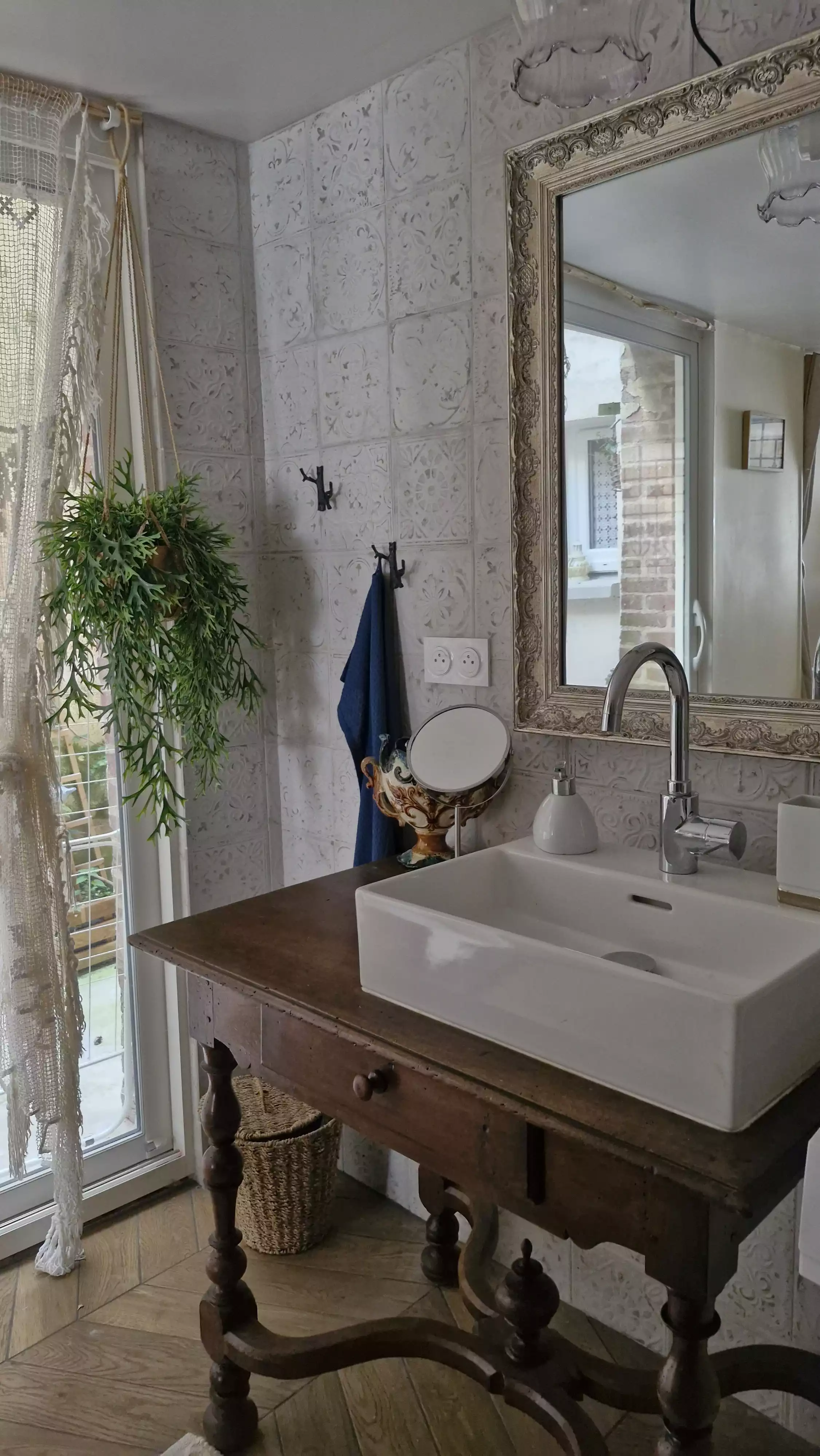 Photo du coin lavabo de la salle de bain, laissant apercevoir la baie vitrée donnant sur le patio privée en arrière plan