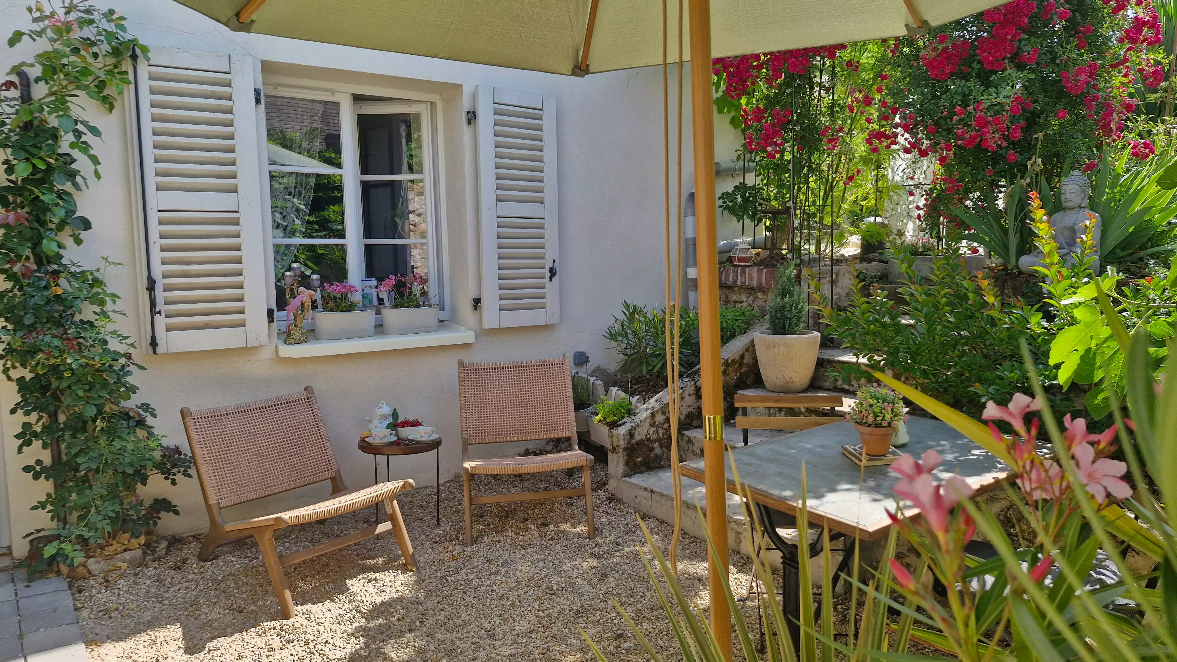 Photo en plan large du salon de jardin et de la table, sous la fenêtre du gîte