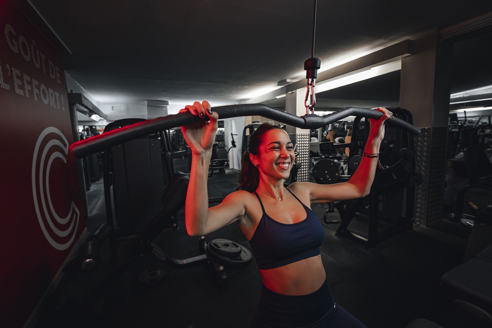 Une adhérente souriante sur une machine de musculation