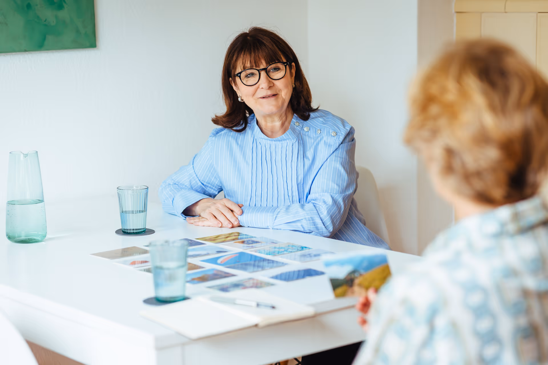 Zwei Frauen im Gespräch an einem Tisch mit Farbkarten und Designmaterialien – Beratungssituation in kreativer Umgebung.