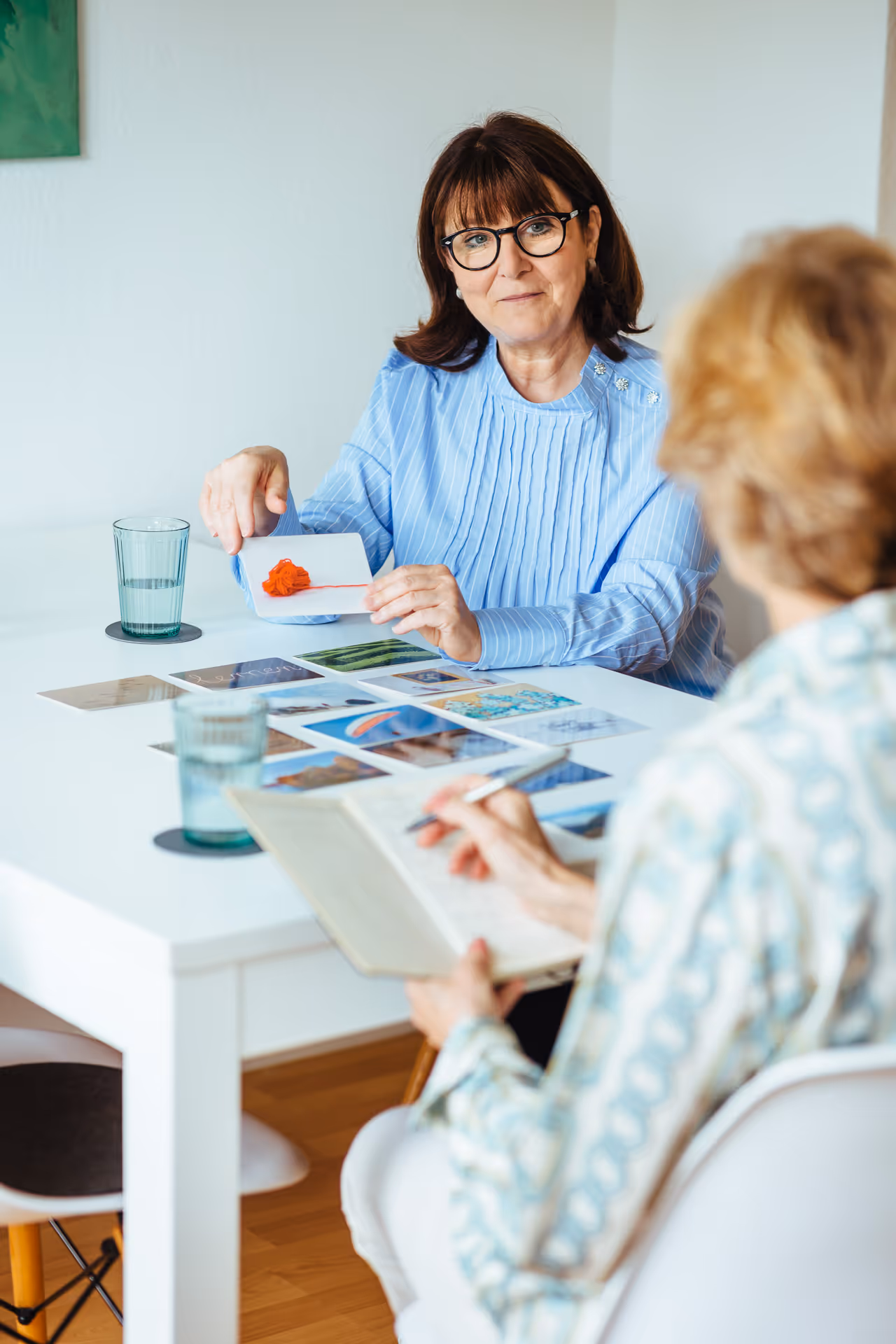 Frau zeigt Farbmuster bei einer Beratung am Tisch – kreative Besprechung mit Farb- und Materialkarten in freundlicher Atmosphäre