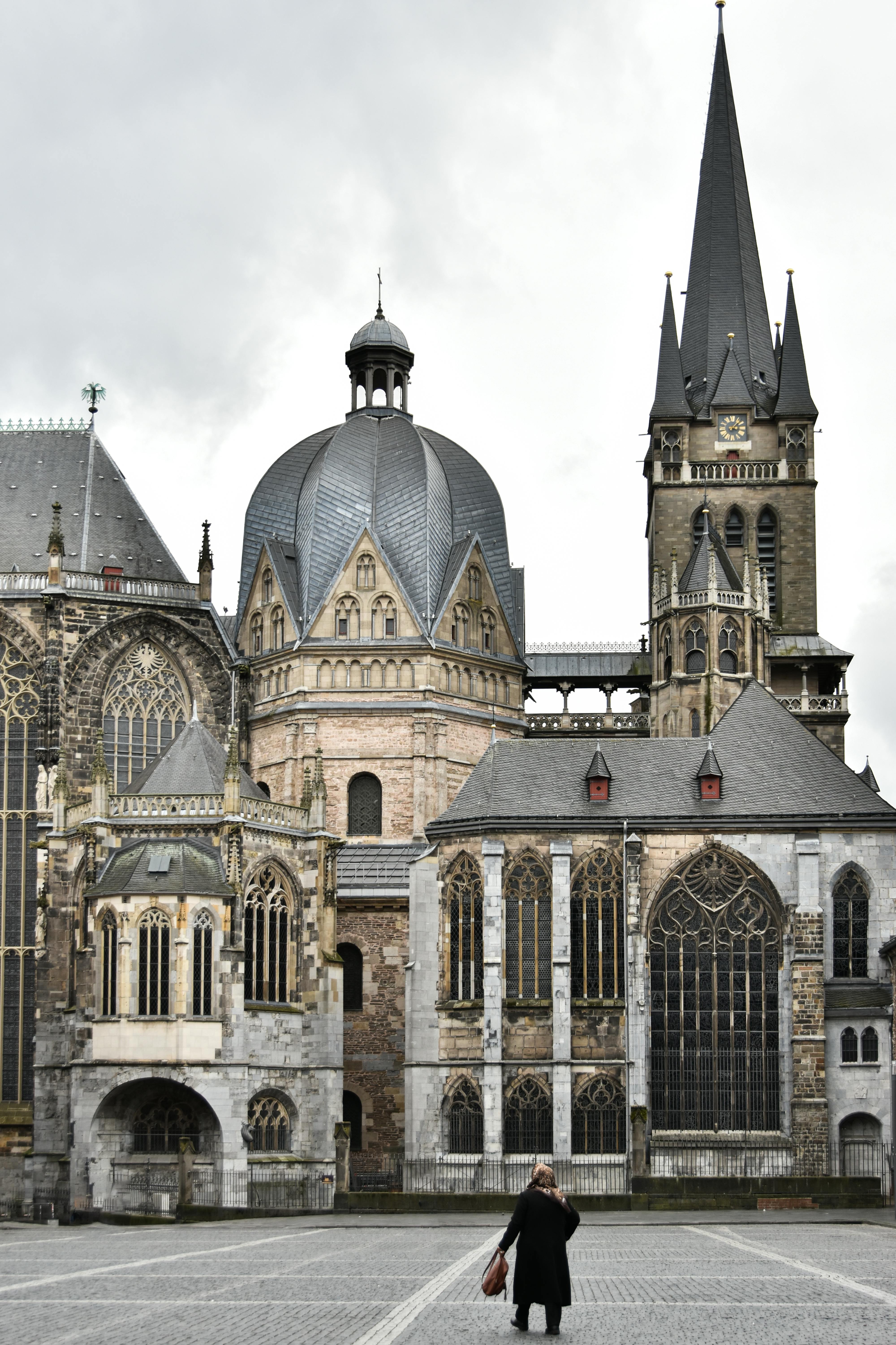 Historische Ansicht des Aachener Doms mit einer Spaziergängerin auf dem leeren Domplatz – kulturelles Wahrzeichen nahe Gut Wolf