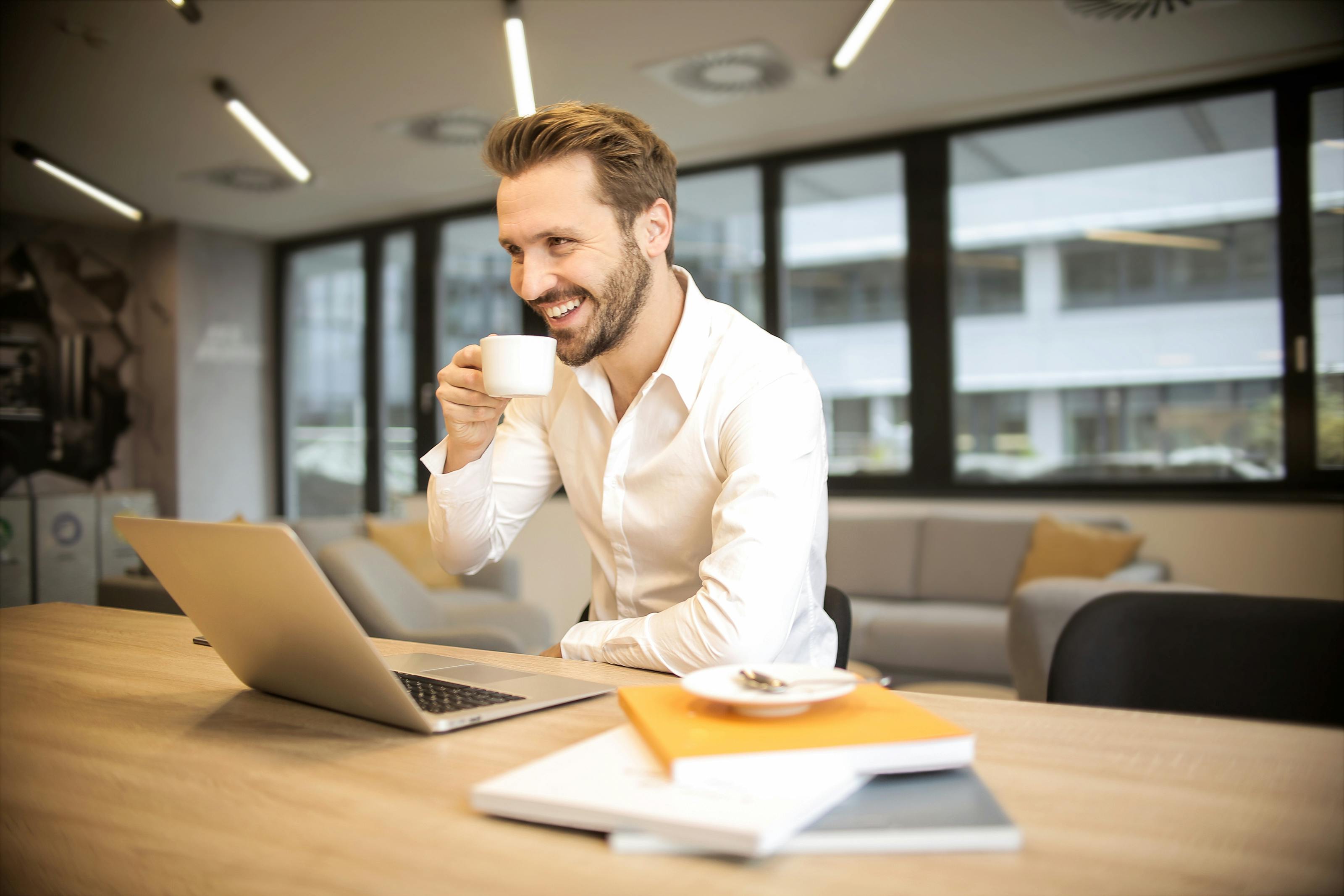 Junge Frau arbeitet konzentriert am Laptop in einem modernen Co-Working-Space mit großen Fenstern.