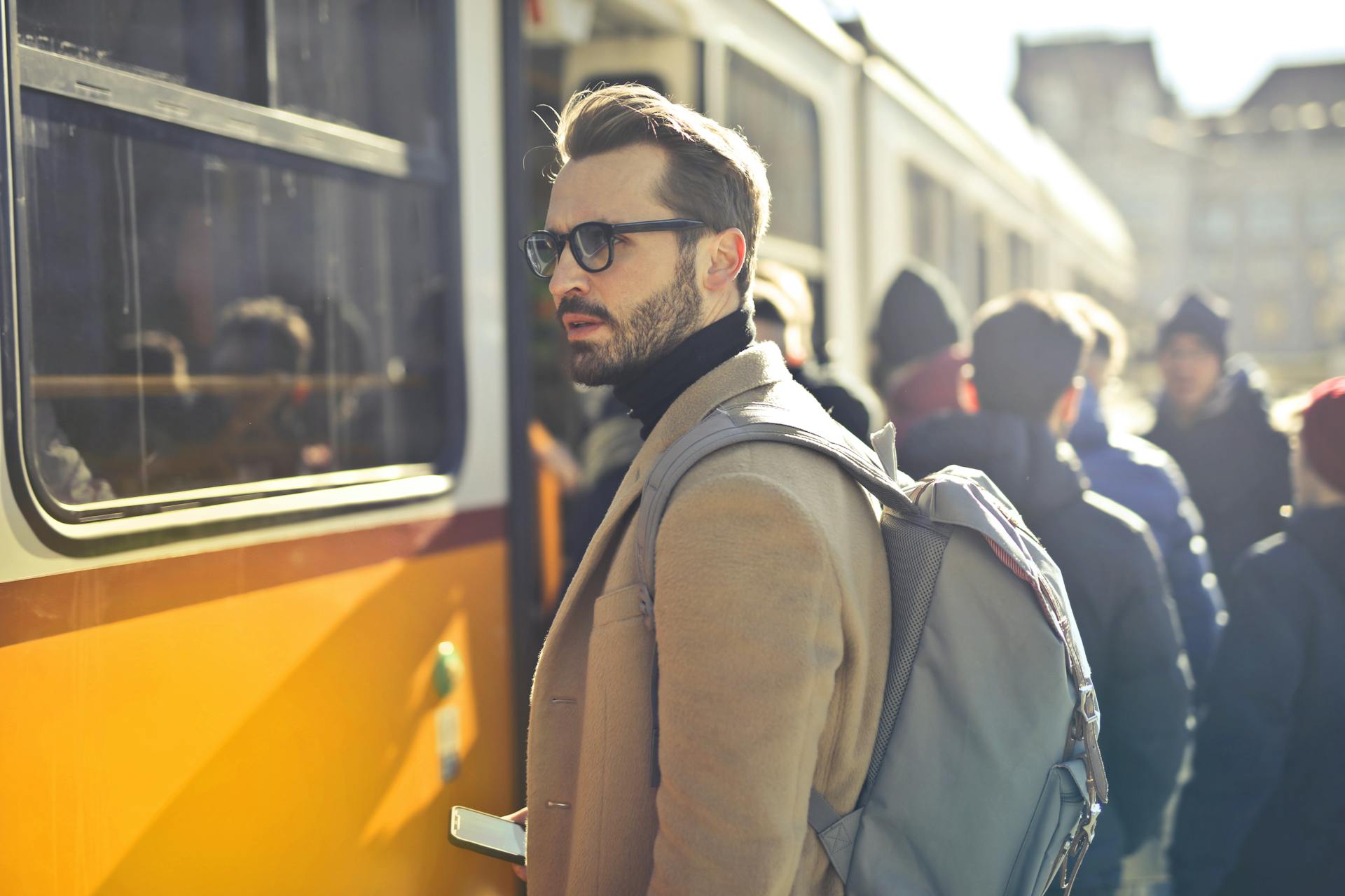 Mann mit Rucksack steigt morgens in eine volle Straßenbahn – Alltag eines Berufspendlers.