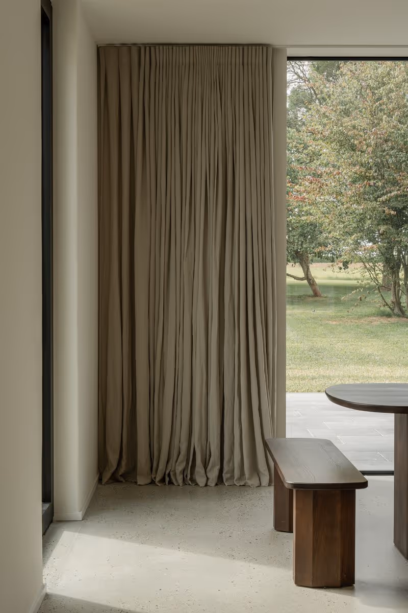 Modern living room with elegant floor-to-ceiling beige curtains framing large windows, creating a cozy and stylish interior design atmosphere.