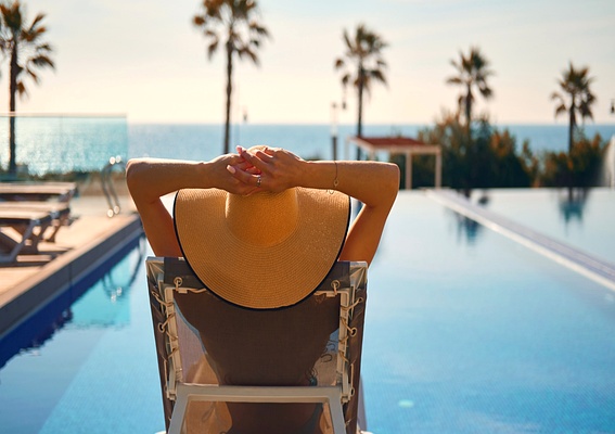 Vakantiegevoel in Spanje, vrouw ontspant bij luxe zwembad met uitzicht op zee – Casamigo Homes verhuurbeheer