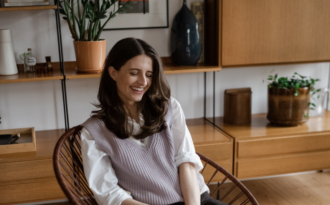 Lydia smiling and sitting on a chair in mid century living room