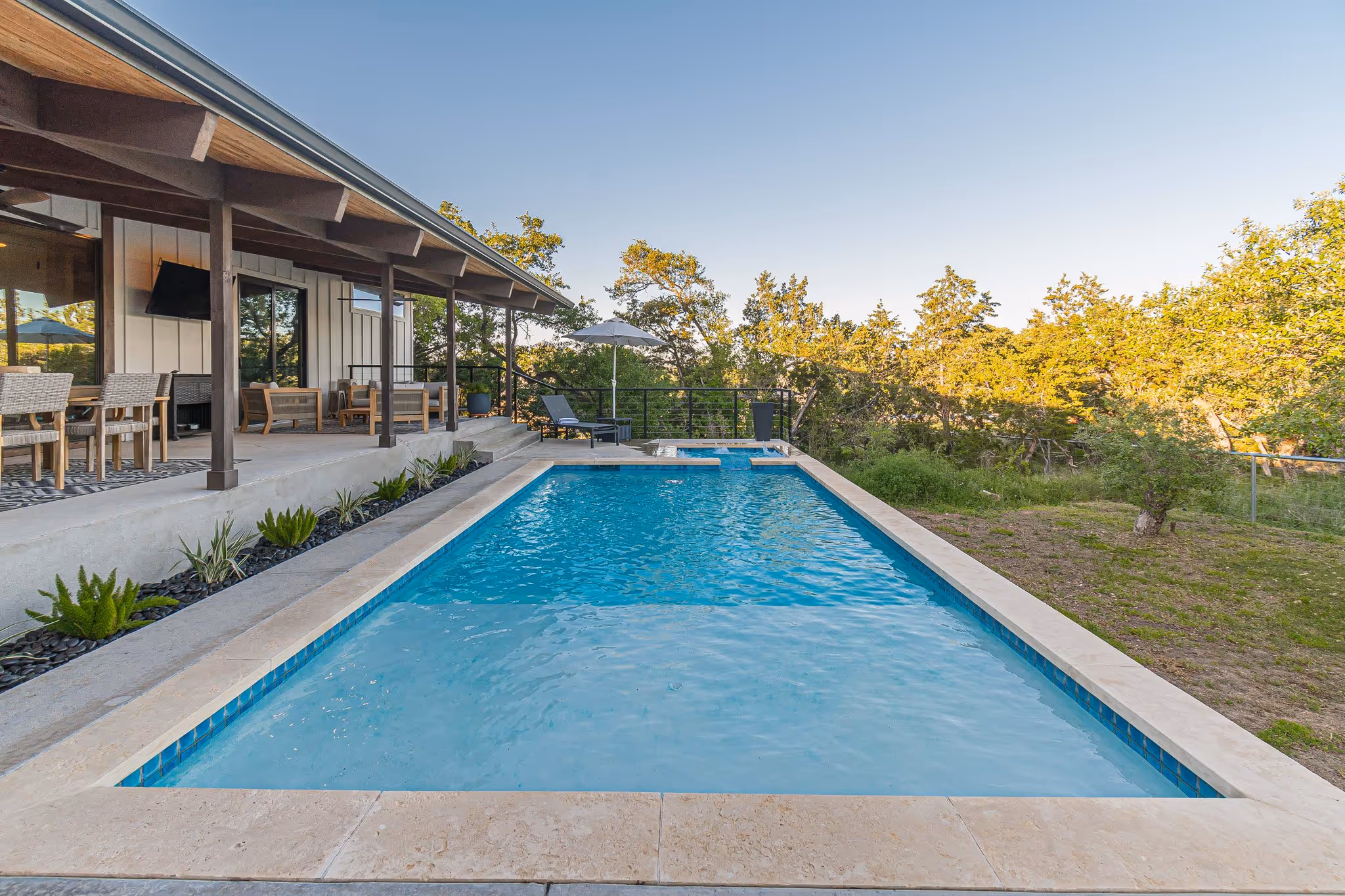A straight down view of a pool with a home and patio on the left.
