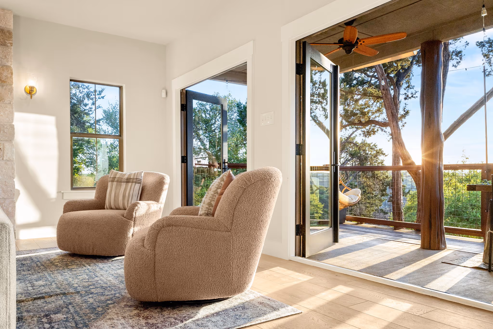 A living room containing 2 chairs with doors opening to a balcony in the background.