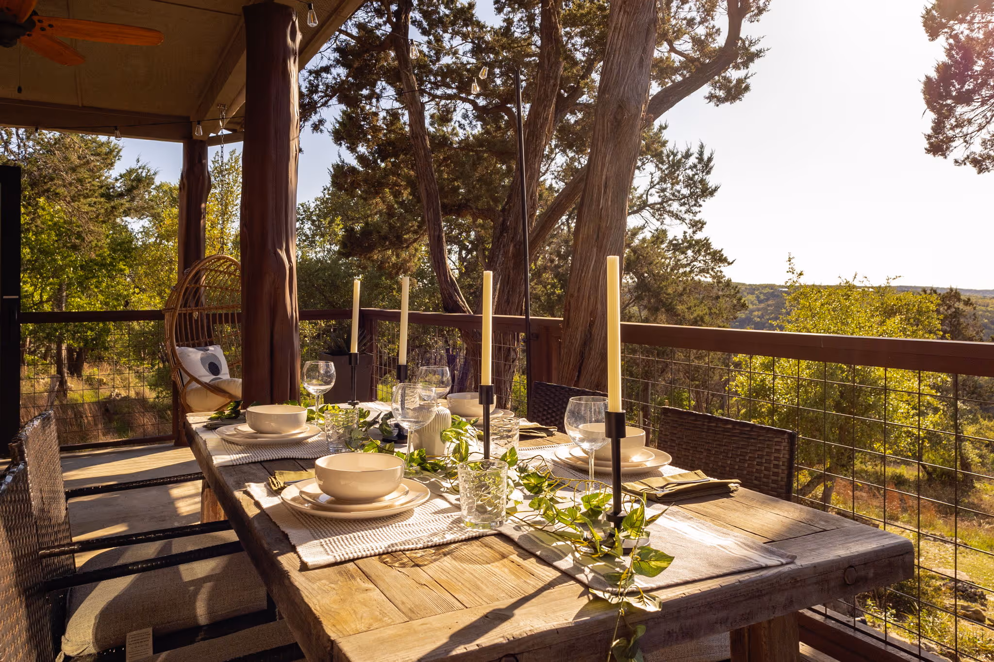 A candle lit dining table on a balcony overlooking the Texas hill country.