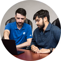 Two IT technicians collaborating over a laptop at a conference table, reviewing managed IT support solutions together