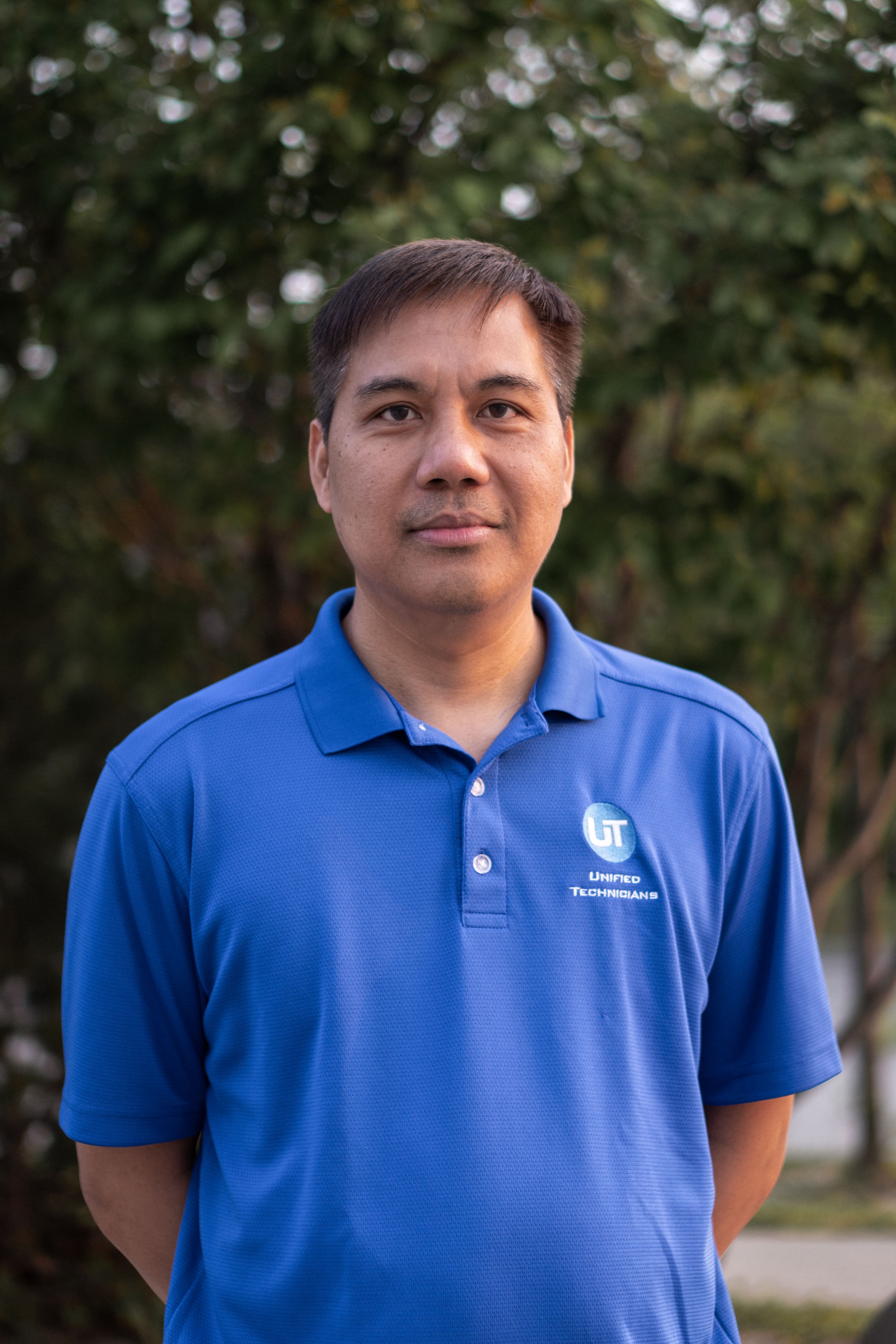 Unified Technicians IT support technician wearing branded blue polo shirt outdoors in Toronto