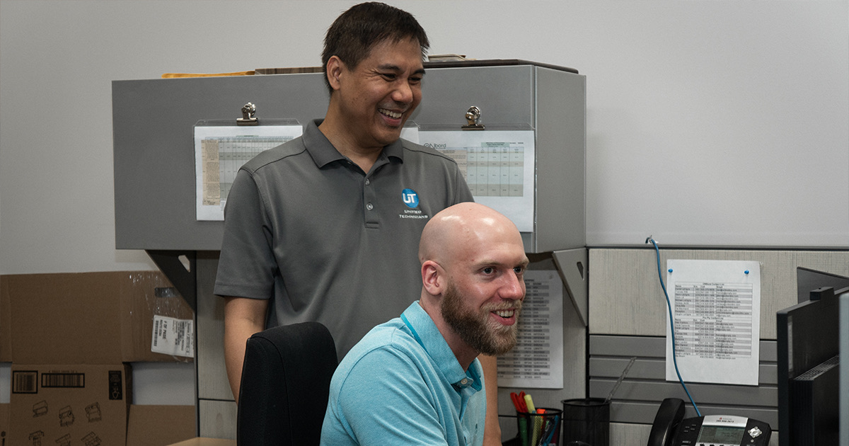 Two Unified Technicians IT support staff smiling at a desk in a Toronto managed services office