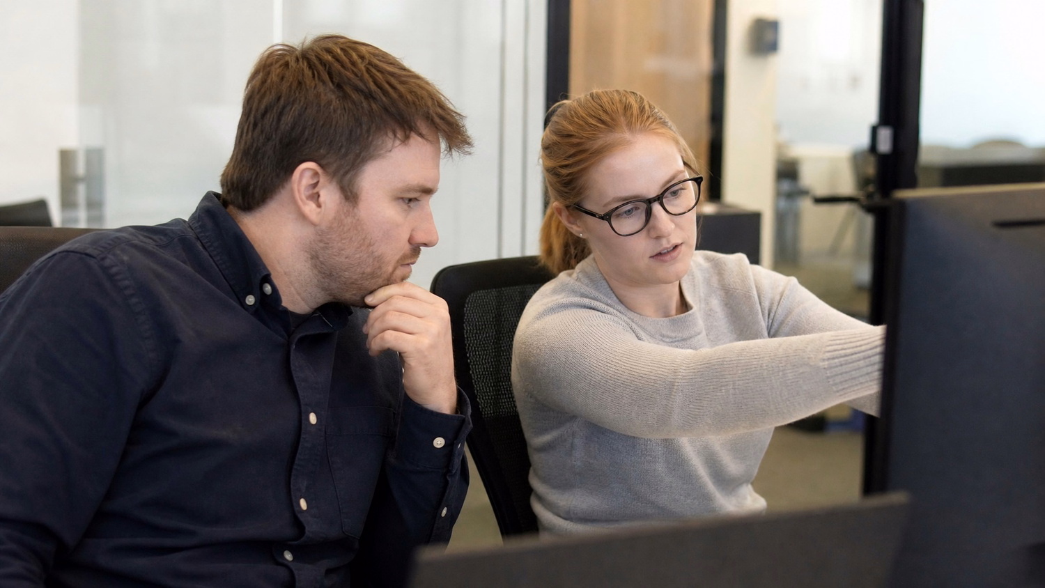 SIDE-BY-SIDE PAIR An IT professional two people seated side by side reviewin