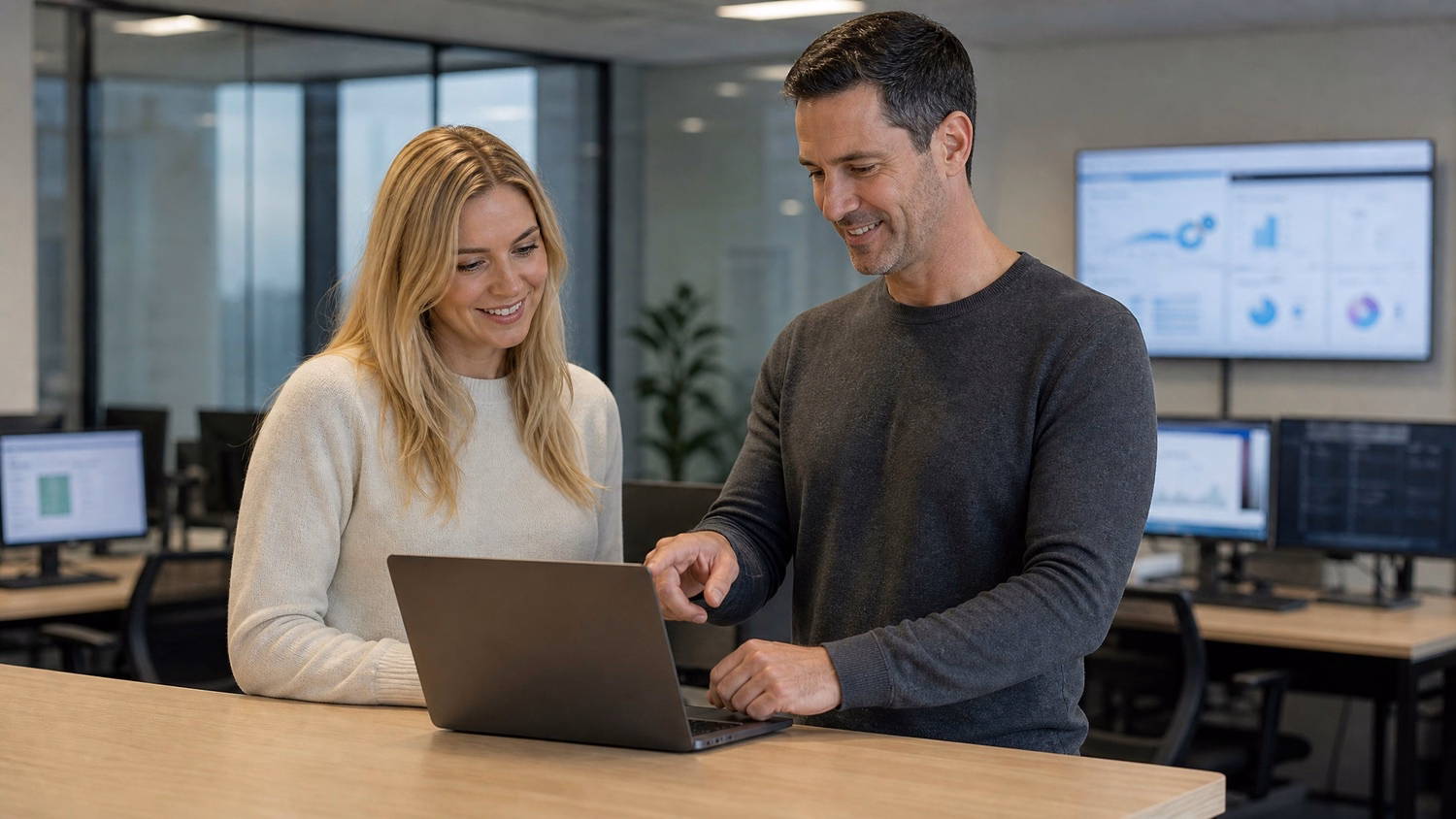 Man and woman review laptop data at standing table 61