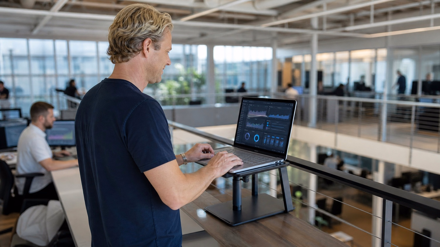Man at balcony rail, viewing network dashboard on laptop 60 chars