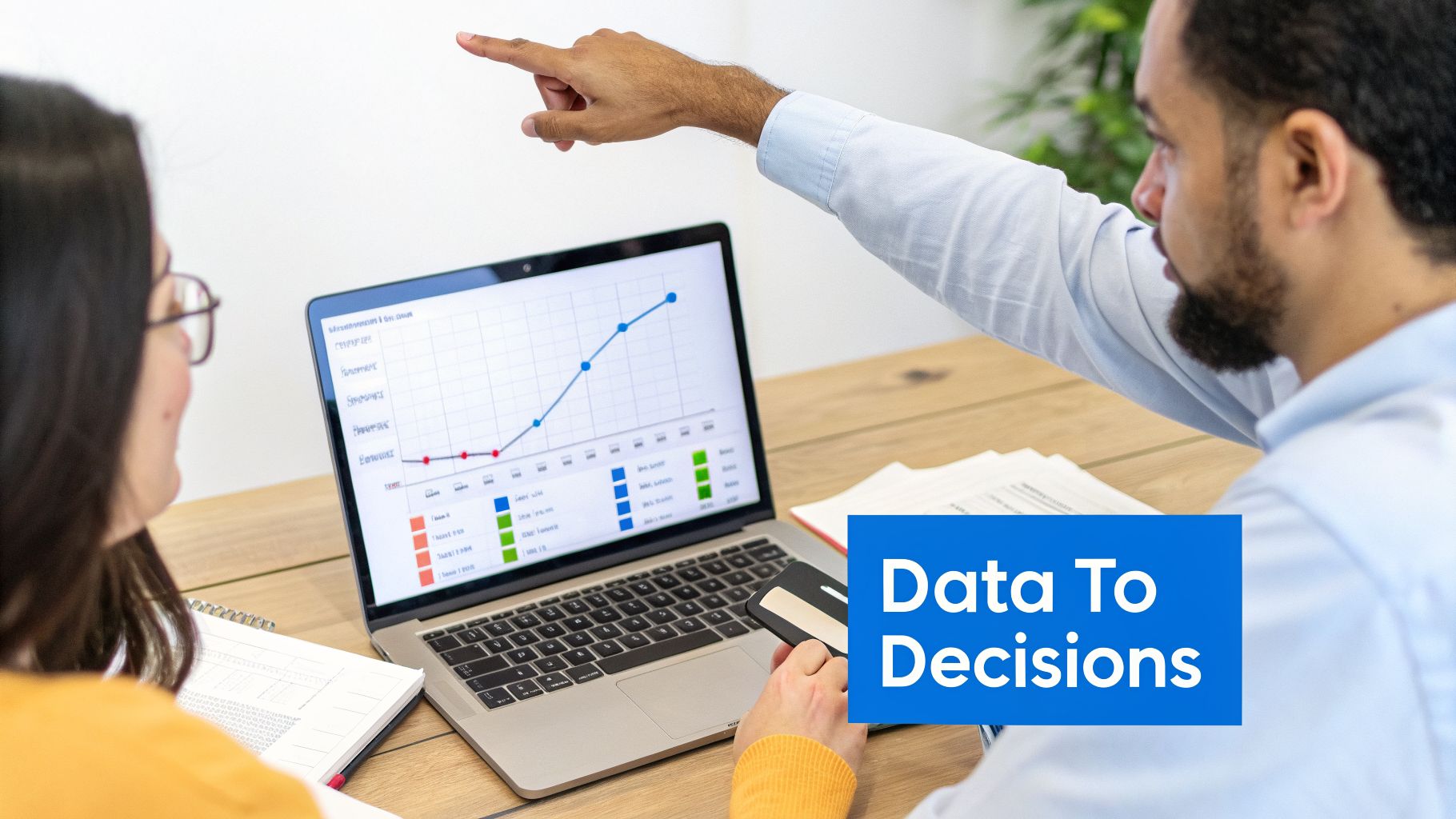 Two colleagues analyze a line graph on a laptop, discussing data for informed decisions.