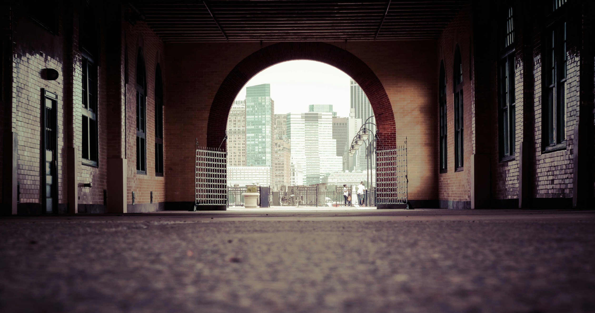 Manchester city skyline framed by a brick archway and industrial corridor.