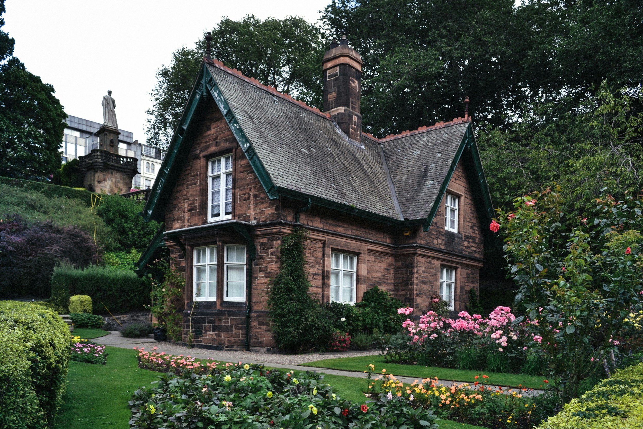 Charming Victorian-style brick cottage with manicured gardens and lush greenery in the UK.
