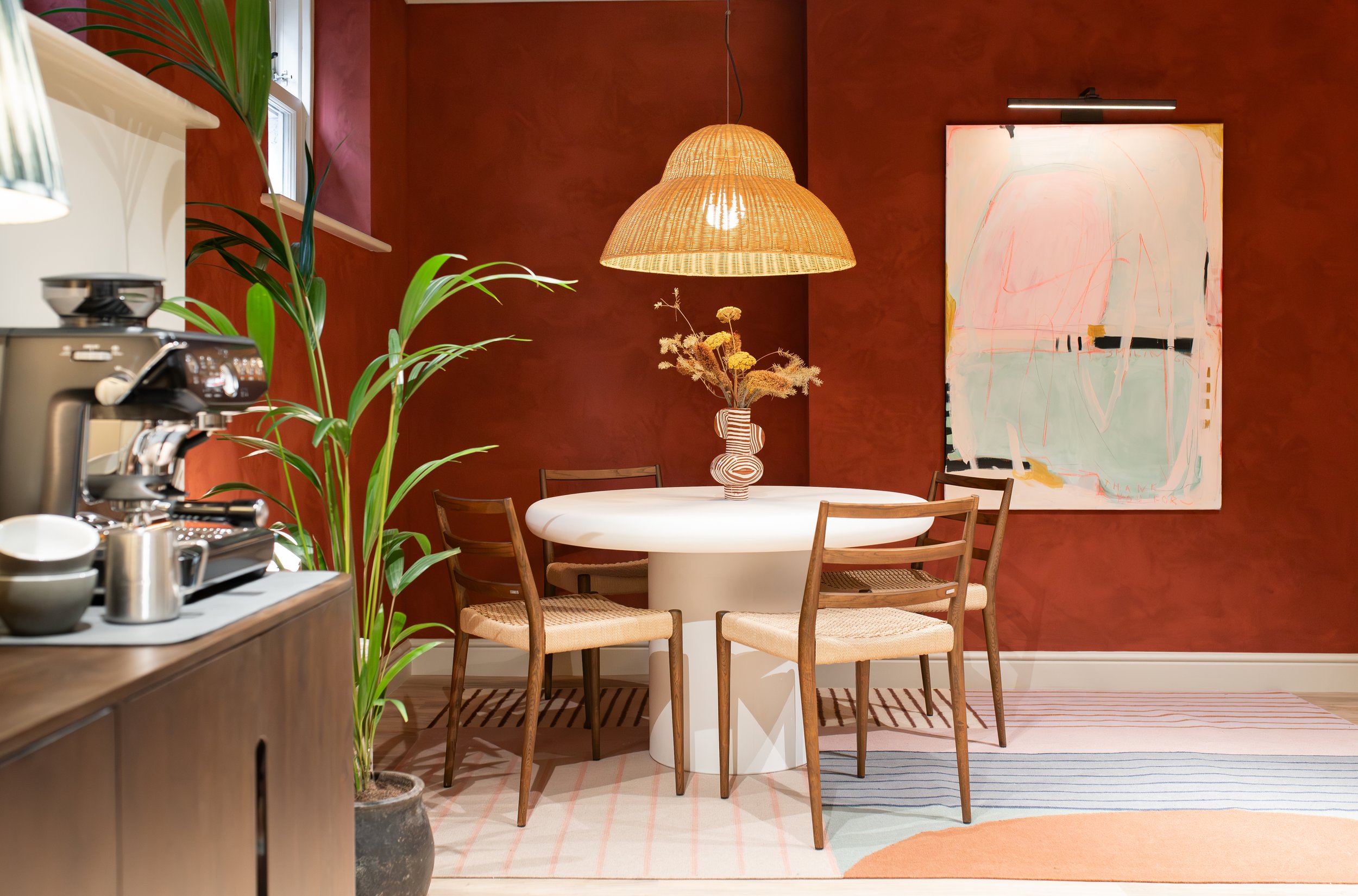 Luxury dining nook with round white table, rattan chairs, and pendant light by TXTURED in Manchester