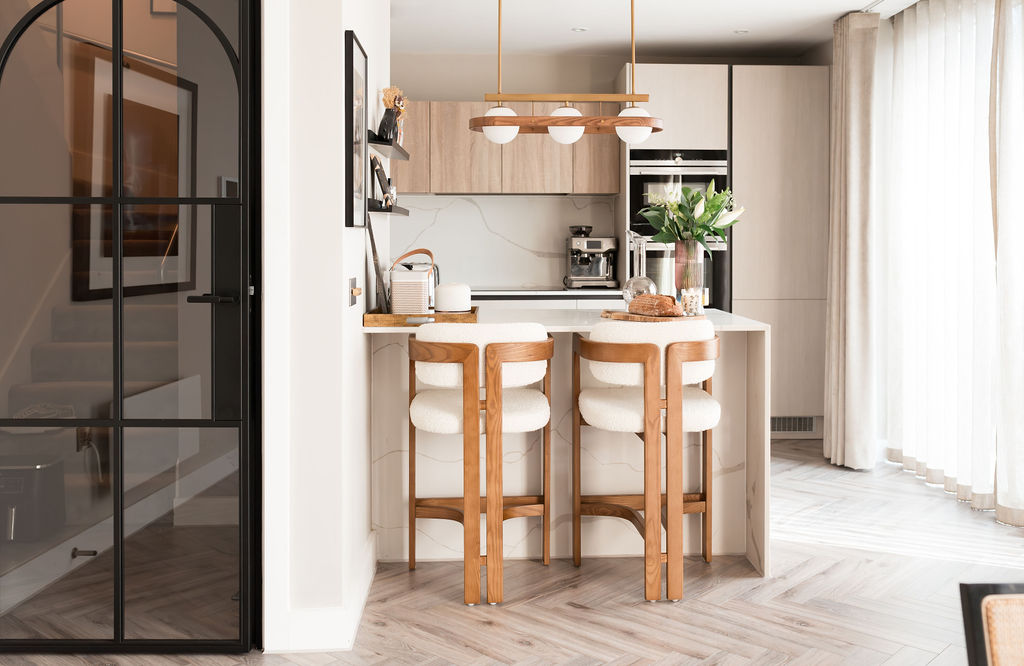 a curved black door on the left hand side with a stunning neutral kitchen. curved walnut chairs.