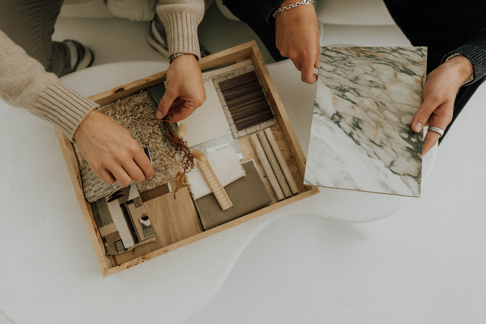 hands over a burl wood tray with material samples in