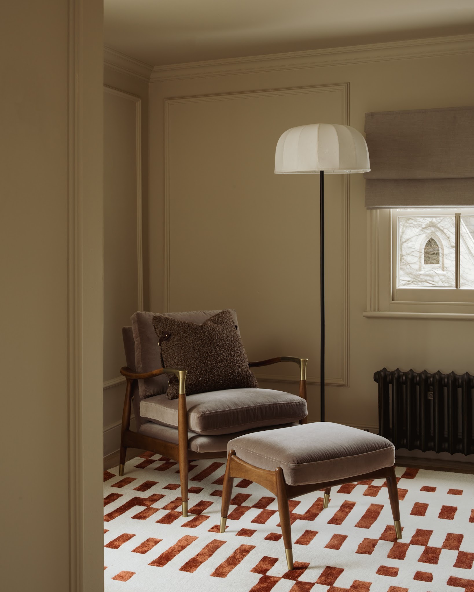Upholstered reading chair beside a lamp in a panelled corner of a London period home