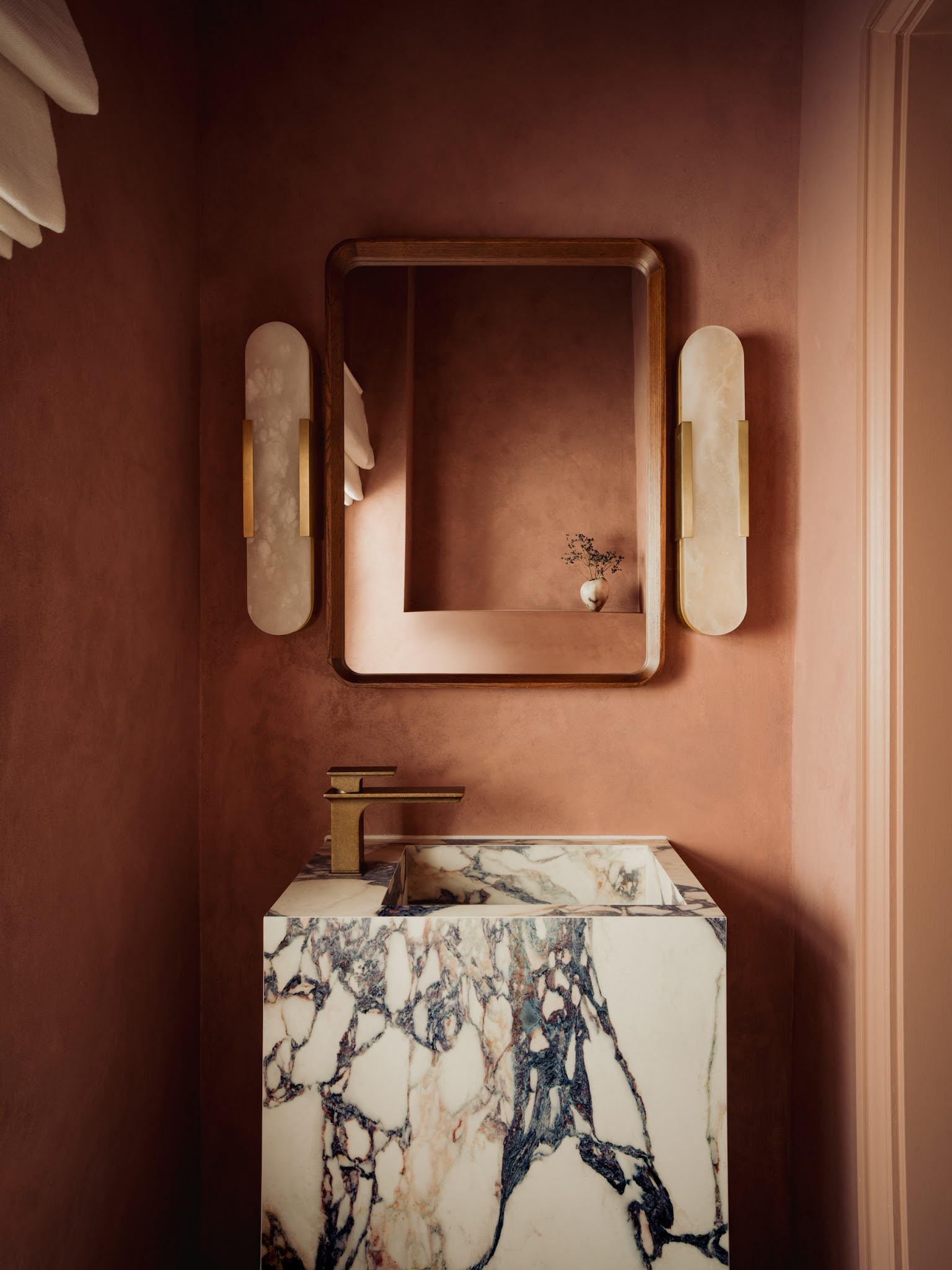 Marble bathroom with brass brassware and wall lights in a luxury London home