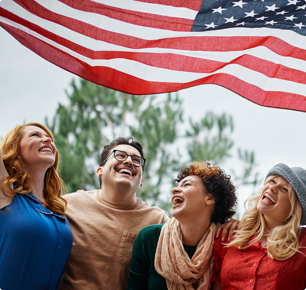 4 peolpe laughing bellow the USA flag