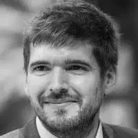 Portrait en gros plan d'un homme souriant avec barbe et cheveux courts.