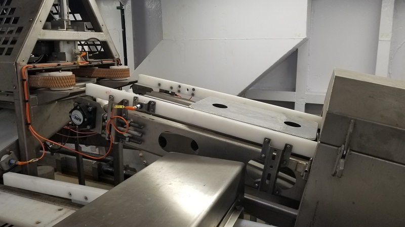 Industrial block ejector with conveyor system and protective housing.