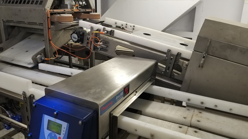 Industrial block ejector with conveyor system and protective housing.