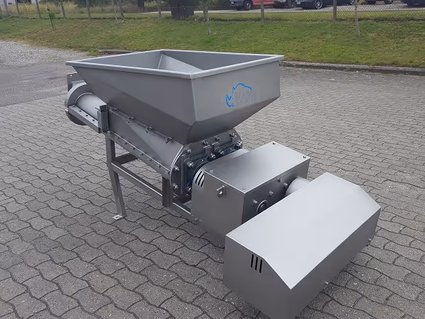 Stainless steel twin screw conveyor on outdoor pavement.