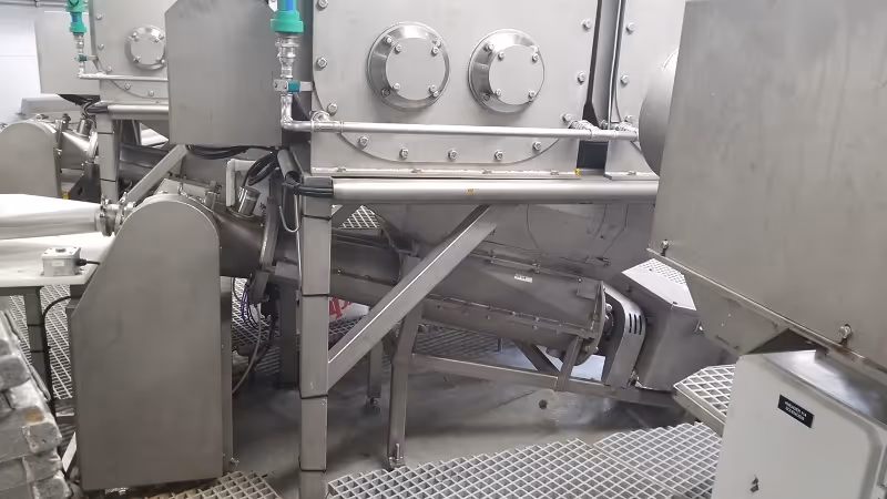 Close-up of twin screw conveyor installed in seafood processing line.
