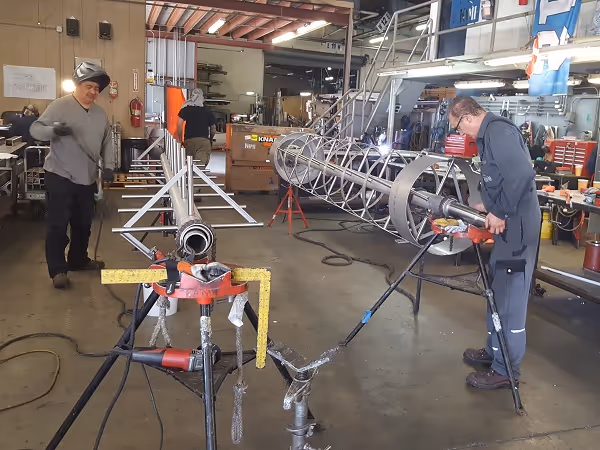 Technician welding components for rotary screen assembly.
