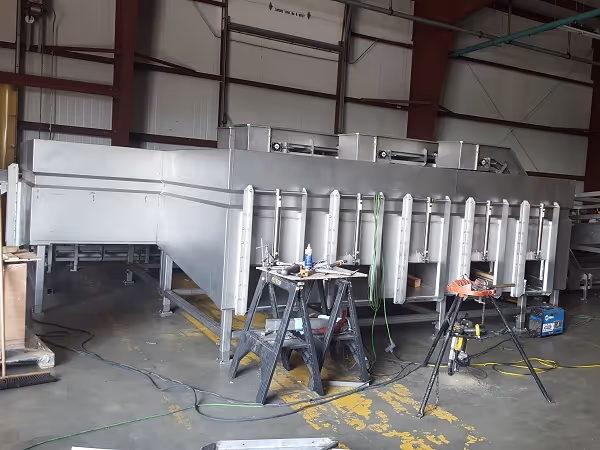 Stainless steel fish sorting machine under construction in workshop.