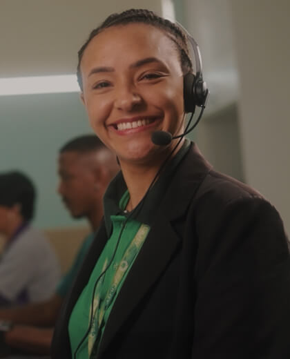 Duas funcionárias da facility com roupa preta e headset, em uma sala com um escrito na parede: "Facility, tem Facility, tá tranquilo"