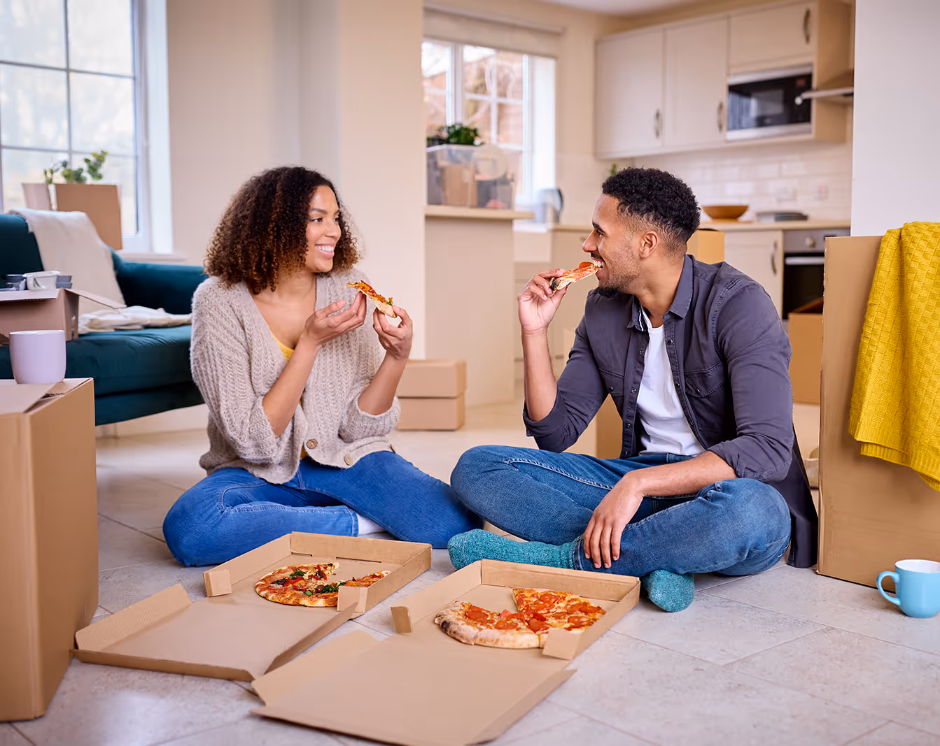 a couple eating pizza on the floor of their new home