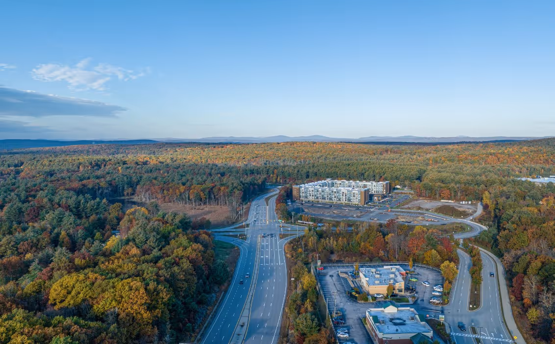 Southern New Hampshire neighborhood street with homes, trees, and local community spaces representing Merrimack, Derry, and Londonderry.