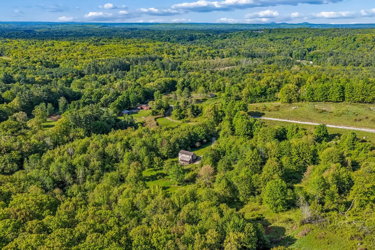 A summer lifestyle image near Joppa Hill in Bedford, New Hampshire, showing a quiet trail, trees, and open recreational space to reflect the town’s residential and outdoor character.