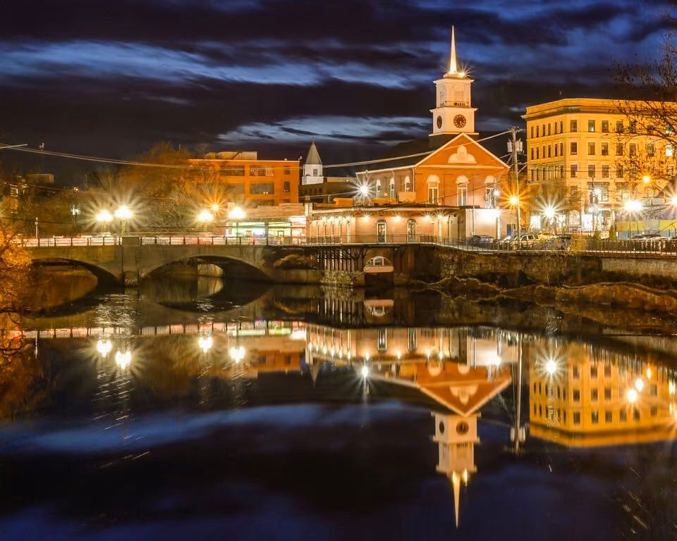 Downtown Nashua, NH during summer, featuring local businesses, historic architecture, pedestrians, and a residential neighborhood backdrop representing the local housing market.