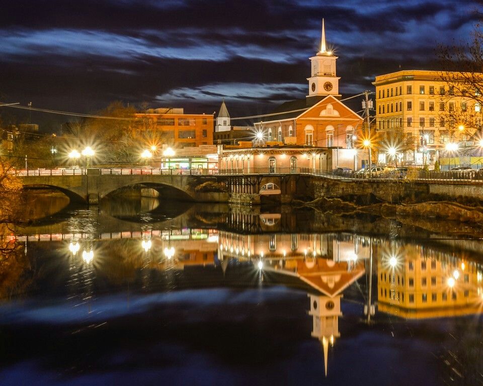 Downtown Nashua, NH during summer, featuring local businesses, historic architecture, pedestrians, and a residential neighborhood backdrop representing the local housing market.