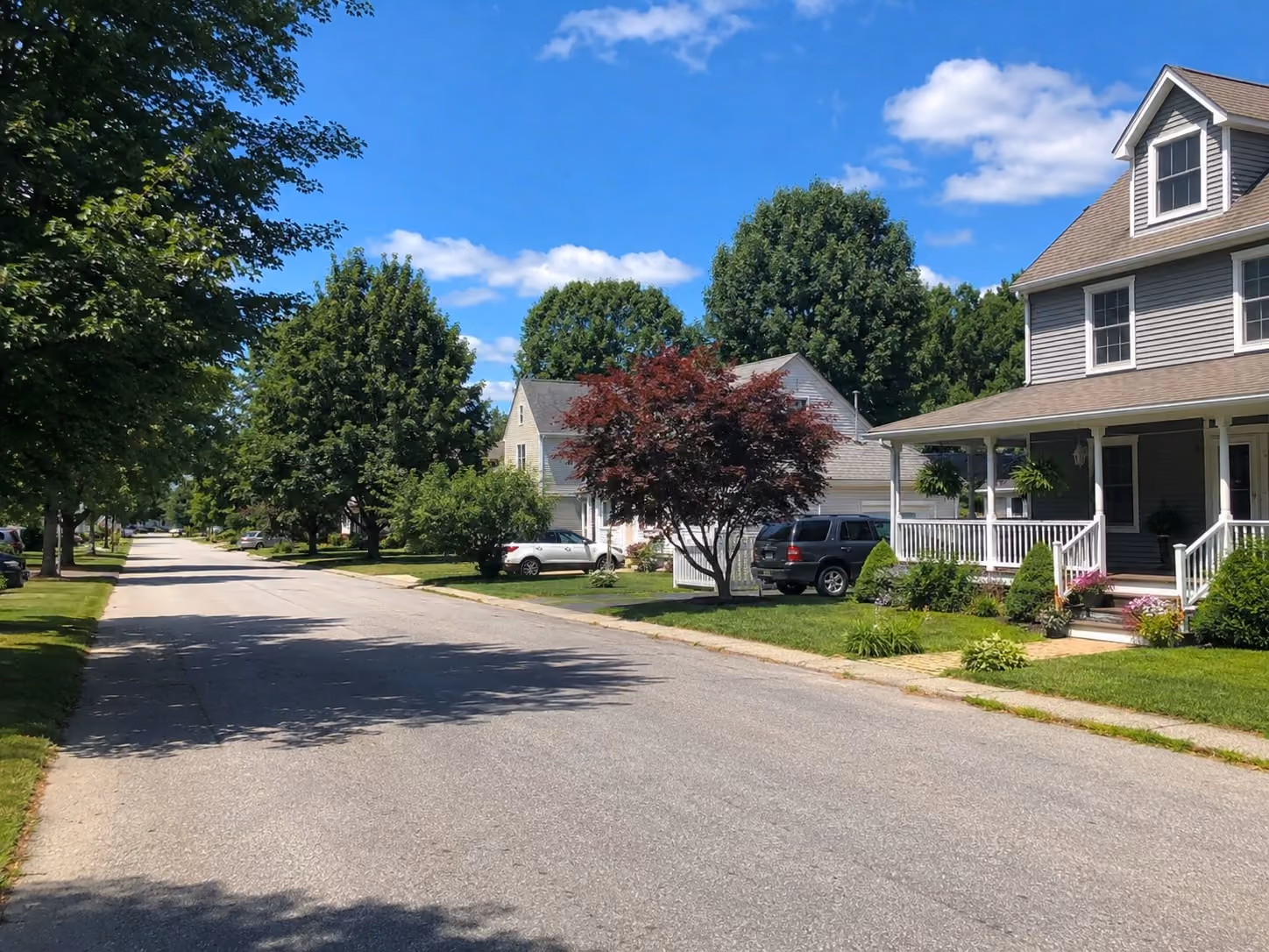 A summer residential street in Derry, New Hampshire with well-kept homes, mature trees, and a clean neighborhood setting that reflects local housing demand and community appeal.