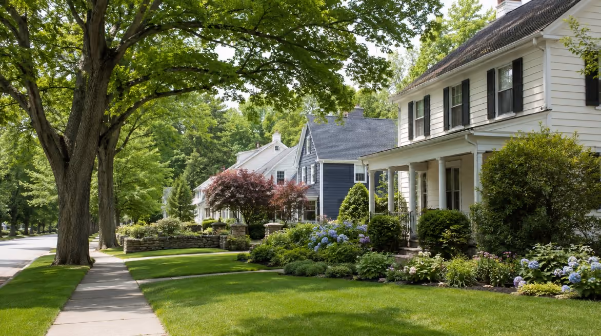 A realistic early-summer New England residential scene near Andover or North Andover, Massachusetts, with mature trees, clean sidewalks, well-kept homes, and a polished neighborhood feel.