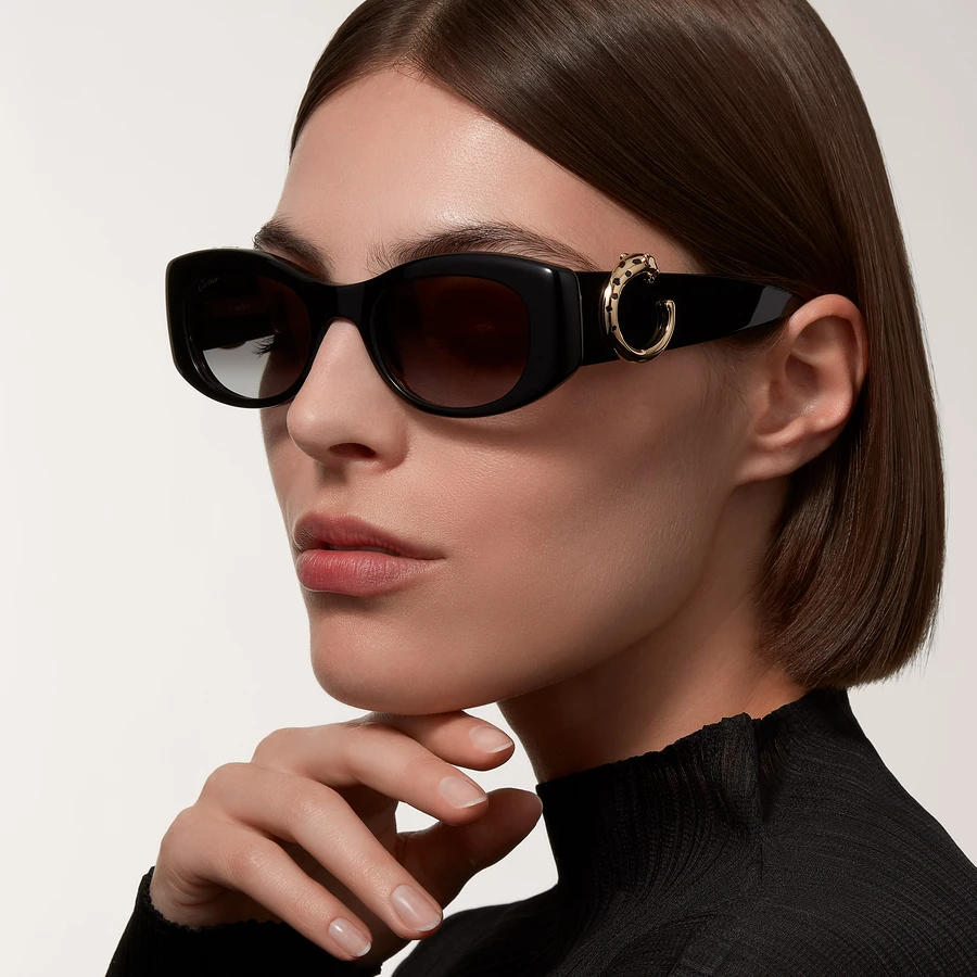 Woman in black sunglasses with elegant gold detail, wearing black turtleneck
