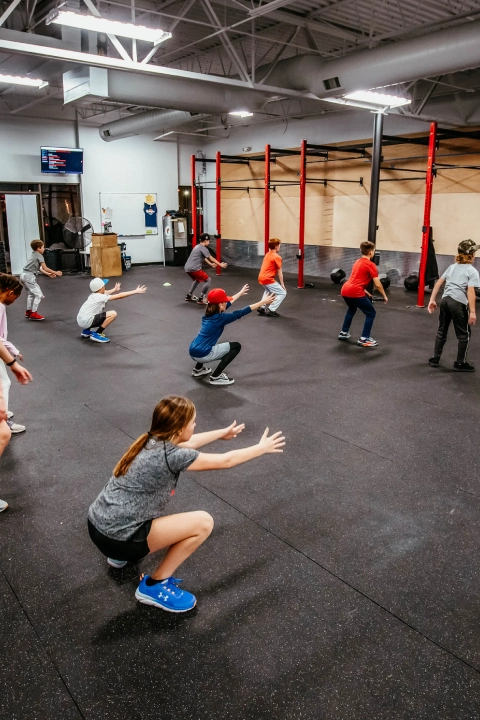 CrossFit gym interior at Game Ready Fitness in Thornton, CO, showcasing workout equipment and athletes in action.