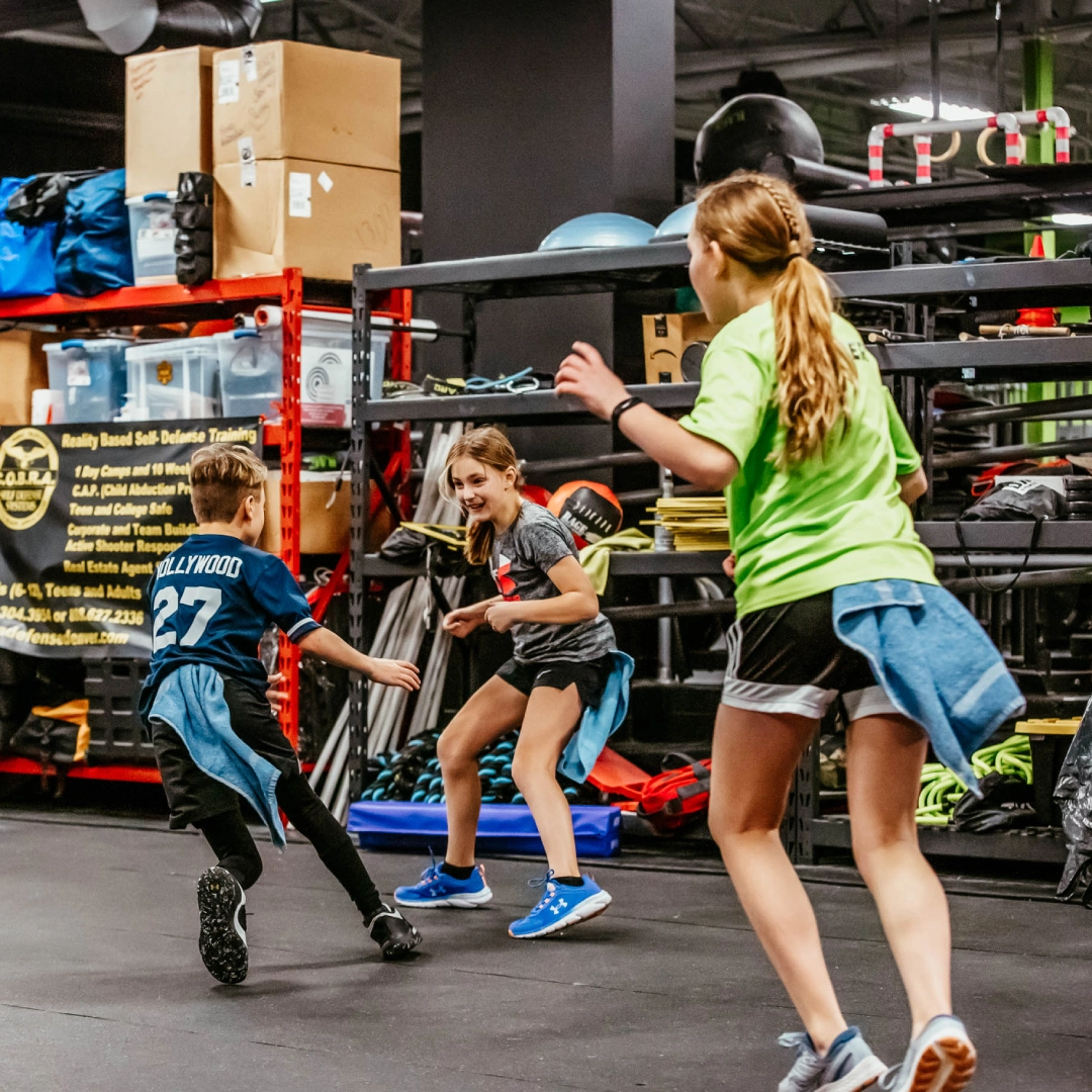Kids running in a gym with a trainer at Game Ready Fitness in Thornton, CO, promoting active play and fitness.