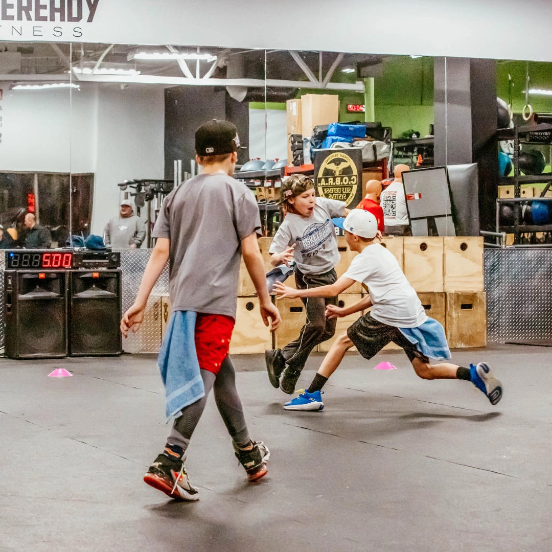 Kids playing soccer indoors at Game Ready Fitness in Thornton, CO, with a ball in a lively gym setting.