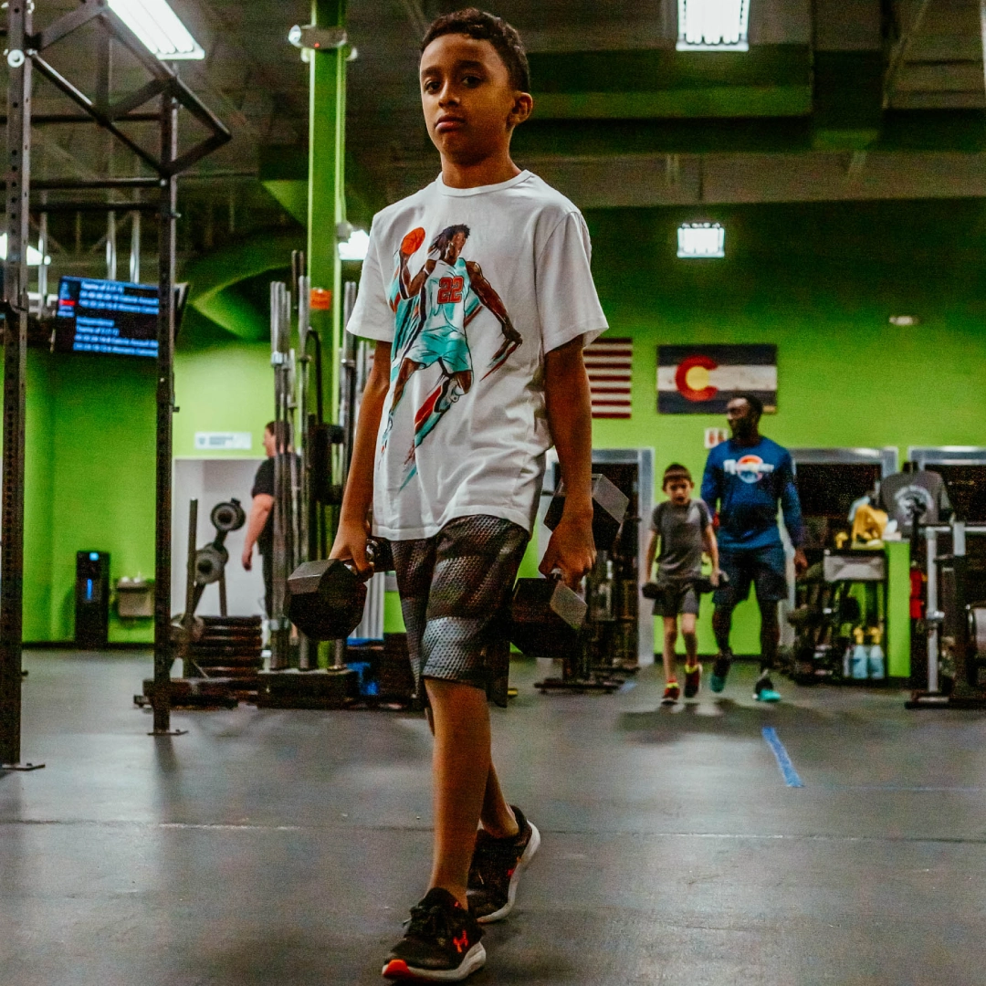 A young boy walks through Game Ready Fitness gym in Thornton, CO, showcasing an active and engaging environment.